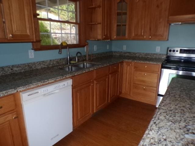 kitchen with a sink, stainless steel electric range oven, brown cabinetry, and dishwasher