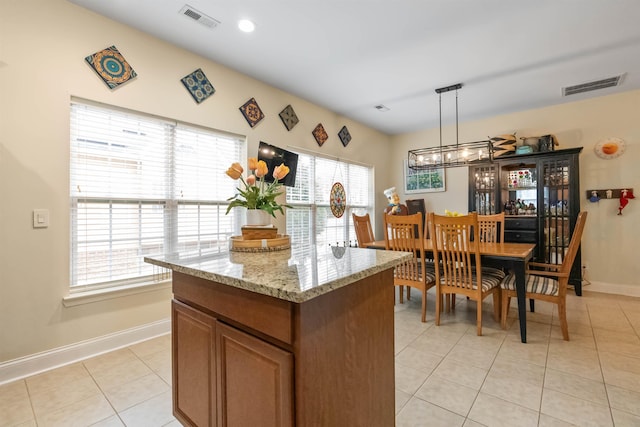 kitchen featuring visible vents, light tile patterned flooring, decorative light fixtures, and brown cabinets