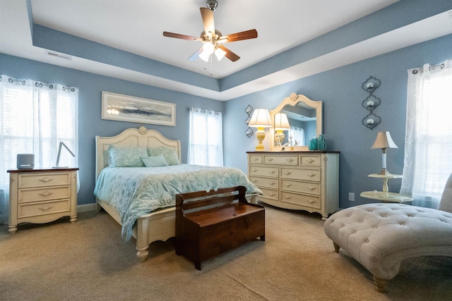 bedroom featuring carpet floors, a tray ceiling, and ceiling fan