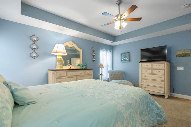 bedroom with carpet floors, a tray ceiling, ceiling fan, and baseboards