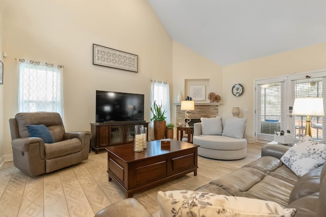 living room featuring high vaulted ceiling, a fireplace, light wood-style flooring, and baseboards