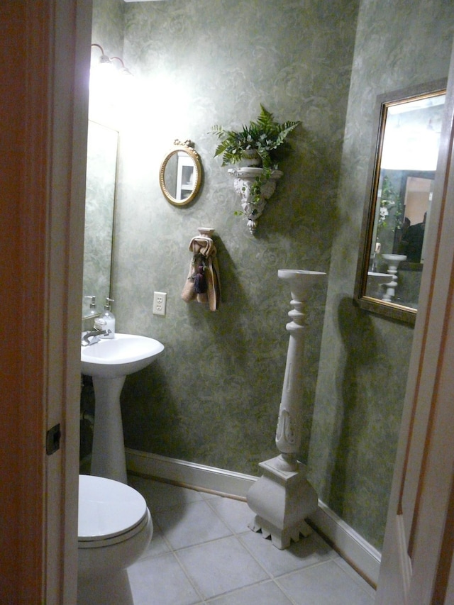 half bathroom featuring baseboards, wallpapered walls, toilet, and tile patterned floors