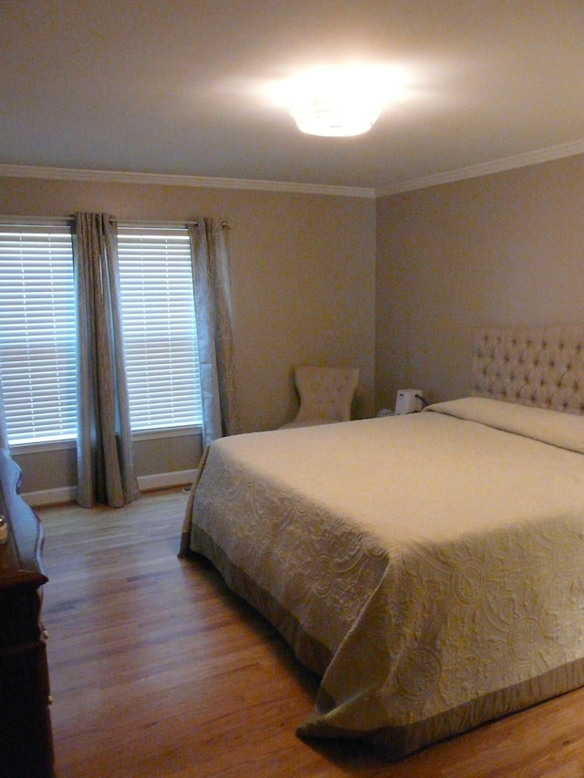 bedroom with crown molding and wood finished floors