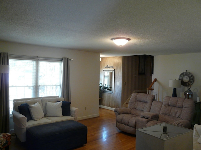 living room featuring a textured ceiling, baseboards, and wood finished floors