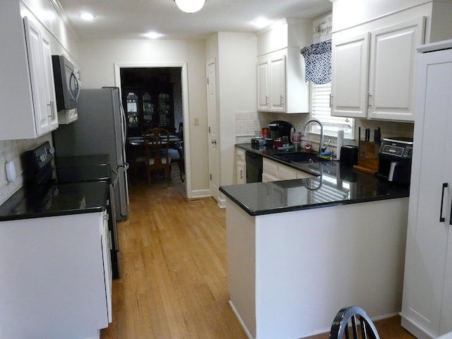 kitchen with a peninsula, a sink, white cabinetry, electric range oven, and dark countertops