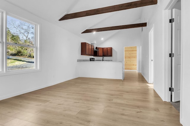 unfurnished living room with baseboards, beamed ceiling, and light wood-style floors