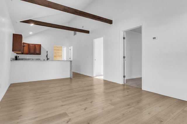 unfurnished living room with high vaulted ceiling, light wood finished floors, and beam ceiling