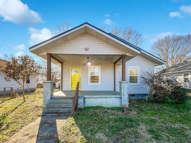 bungalow-style house with covered porch, a front yard, and fence