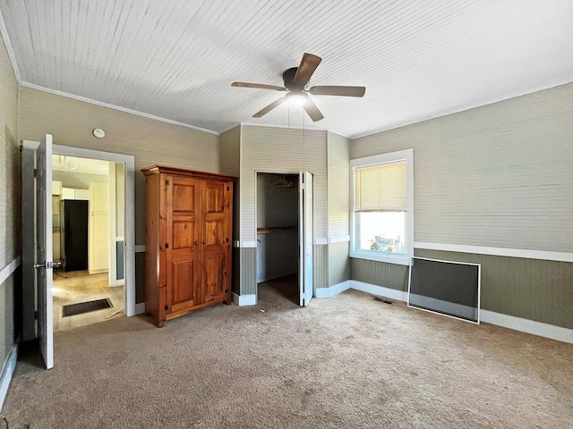 unfurnished bedroom featuring visible vents, ceiling fan, ornamental molding, freestanding refrigerator, and carpet flooring