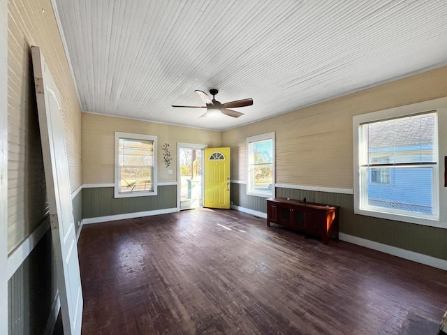 empty room featuring wainscoting, dark wood finished floors, a ceiling fan, and baseboards