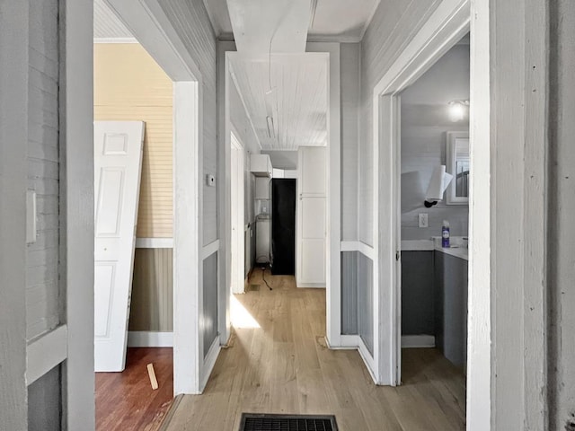 hall with visible vents, light wood-type flooring, attic access, and baseboards