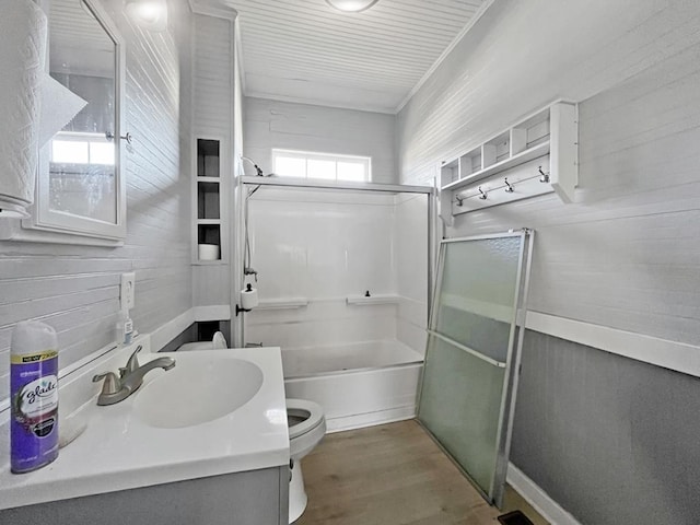 full bath with enclosed tub / shower combo, toilet, wooden walls, wood finished floors, and vanity