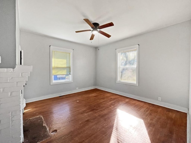 unfurnished living room featuring wood finished floors, plenty of natural light, a fireplace, and baseboards