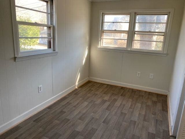 unfurnished room featuring dark wood-style floors and baseboards