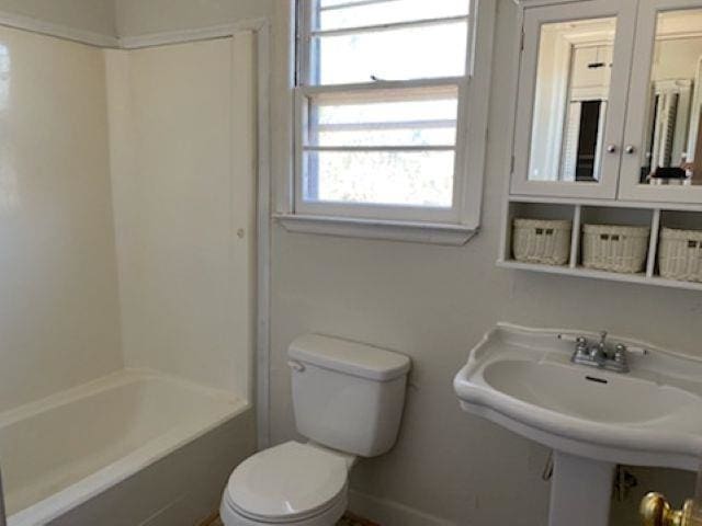 full bathroom featuring toilet, baseboards, tub / shower combination, and a sink