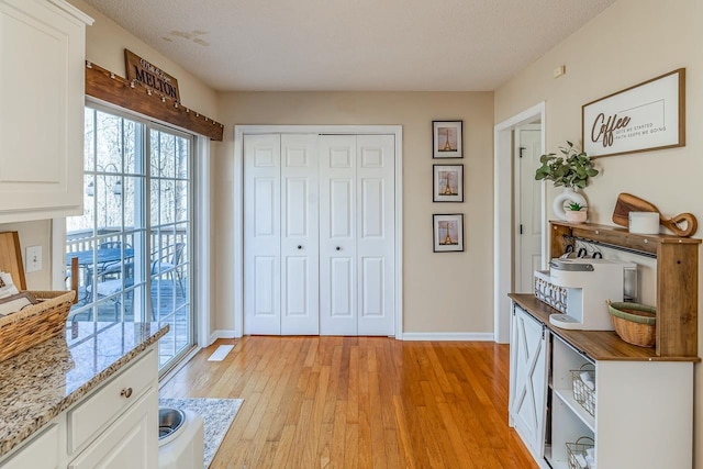 interior space featuring light wood-type flooring, baseboards, and a textured ceiling