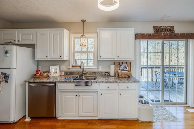 kitchen with a sink, white cabinetry, stainless steel dishwasher, freestanding refrigerator, and pendant lighting