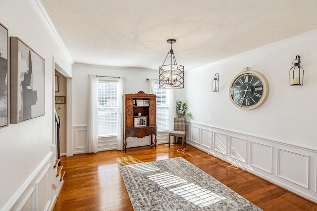 sitting room with an inviting chandelier, crown molding, a textured ceiling, and wood finished floors