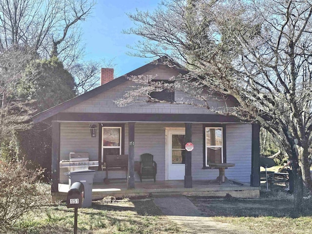 bungalow-style home featuring covered porch and a chimney