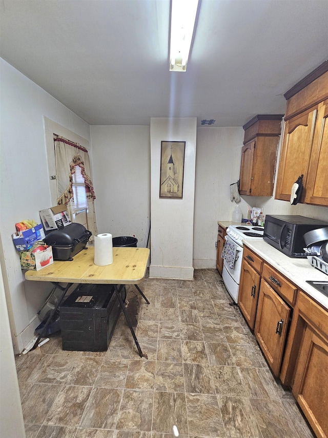 kitchen with black microwave, light countertops, white range with electric cooktop, and brown cabinetry