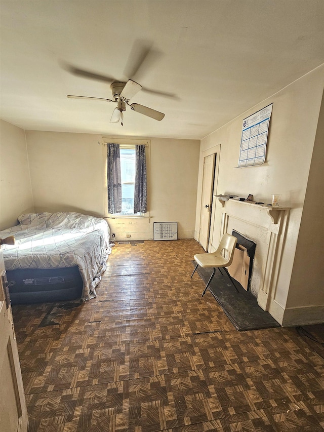 unfurnished bedroom with a fireplace with raised hearth and a ceiling fan