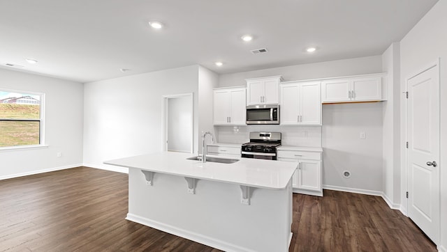 kitchen with appliances with stainless steel finishes, a sink, dark wood-style flooring, white cabinets, and recessed lighting