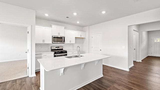 kitchen with appliances with stainless steel finishes, a sink, a kitchen island with sink, white cabinetry, and dark wood-style floors