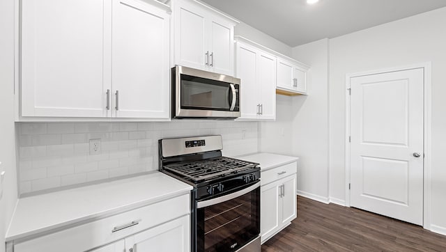 kitchen featuring stainless steel appliances, decorative backsplash, white cabinets, dark wood-type flooring, and baseboards