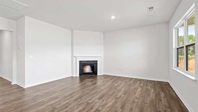 unfurnished living room with wood finished floors, a glass covered fireplace, baseboards, and recessed lighting
