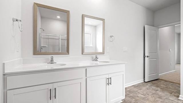 bathroom with an enclosed shower, double vanity, and baseboards