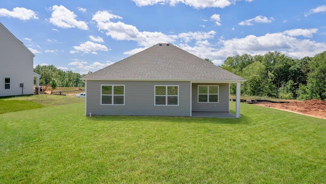 rear view of property featuring a yard, roof with shingles, and a patio area