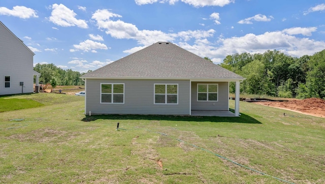 rear view of house featuring a yard, roof with shingles, and a patio