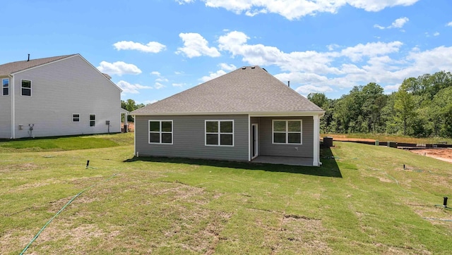 rear view of house with a lawn, a patio, and a shingled roof
