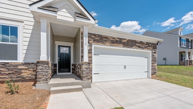 property entrance featuring stone siding, a garage, and concrete driveway