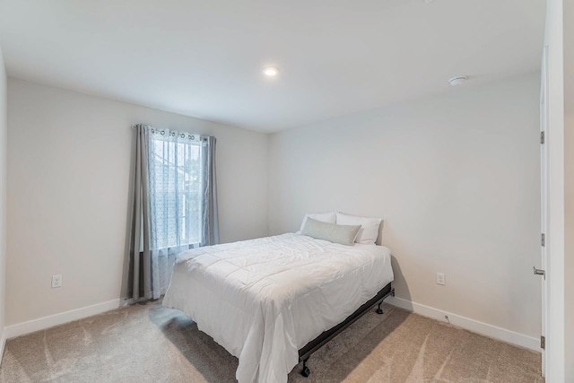 bedroom featuring light colored carpet and baseboards