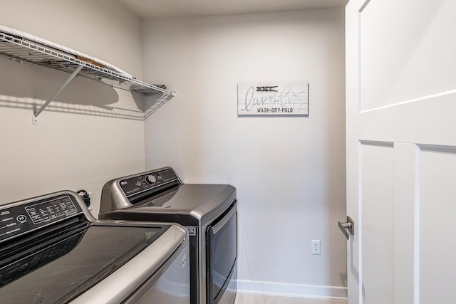 washroom featuring laundry area, baseboards, and washer and dryer