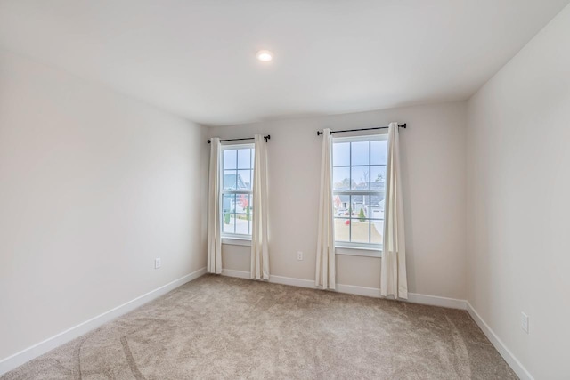 spare room with recessed lighting, light carpet, and baseboards