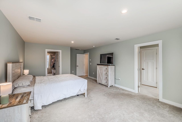 bedroom featuring a walk in closet, recessed lighting, light colored carpet, visible vents, and baseboards