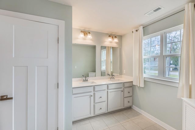 bathroom featuring tile patterned flooring, visible vents, a sink, and double vanity