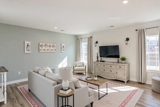 living room featuring light wood-type flooring, visible vents, and a healthy amount of sunlight