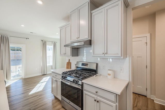 kitchen with light countertops, white cabinetry, gas range, and under cabinet range hood