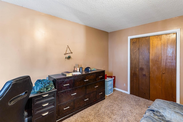 carpeted bedroom with a textured ceiling, a closet, and baseboards