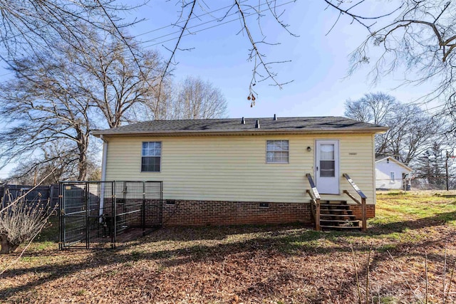 rear view of house with entry steps, crawl space, a gate, and fence