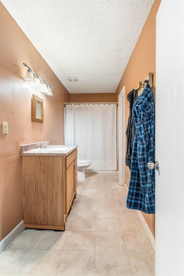 full bathroom with a textured ceiling, tile patterned flooring, toilet, vanity, and baseboards