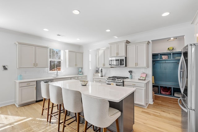 kitchen featuring light wood-style flooring, visible vents, a kitchen breakfast bar, light countertops, and appliances with stainless steel finishes