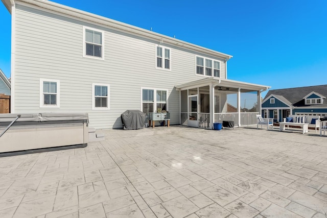 back of property with a patio, a sunroom, and a hot tub