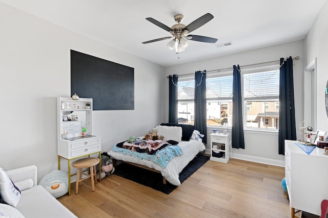 bedroom with a ceiling fan, light wood-style flooring, visible vents, and baseboards