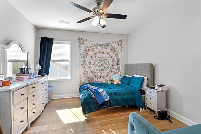 bedroom with baseboards, visible vents, ceiling fan, and light wood finished floors