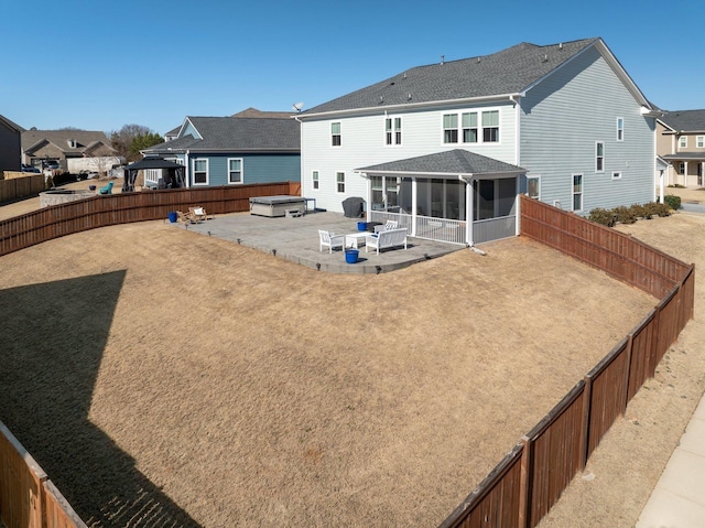 rear view of house with a fenced backyard, a sunroom, a residential view, a patio area, and a hot tub