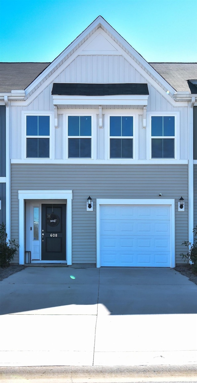 view of front of home with a garage, concrete driveway, board and batten siding, and roof with shingles